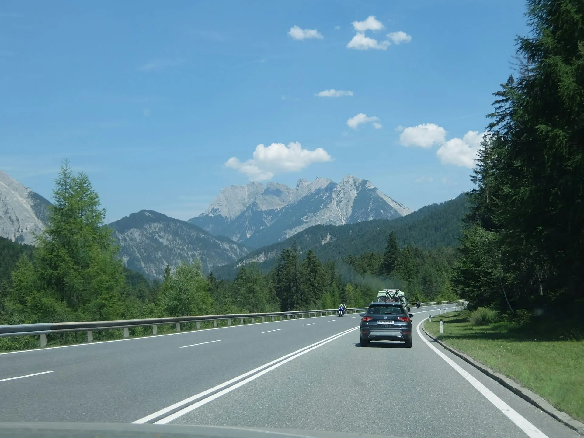 Un coche eléctrico en una carretera de montaña con curvas en los Alpes